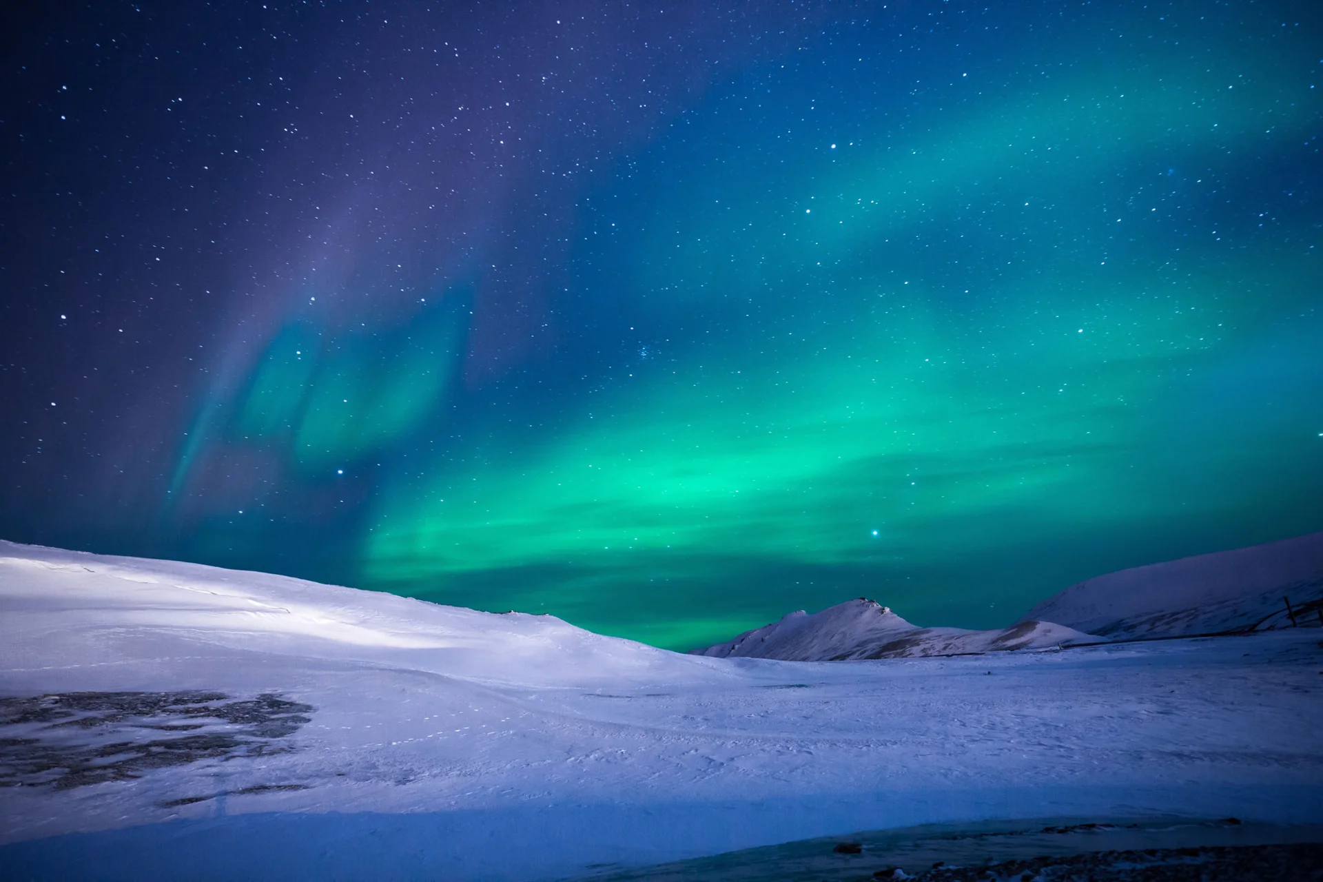 Green and blue Northern Lights above a snow-covered landscape