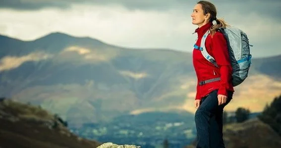 Lowri wearing a red outdoor jacket and backpack in the mountains