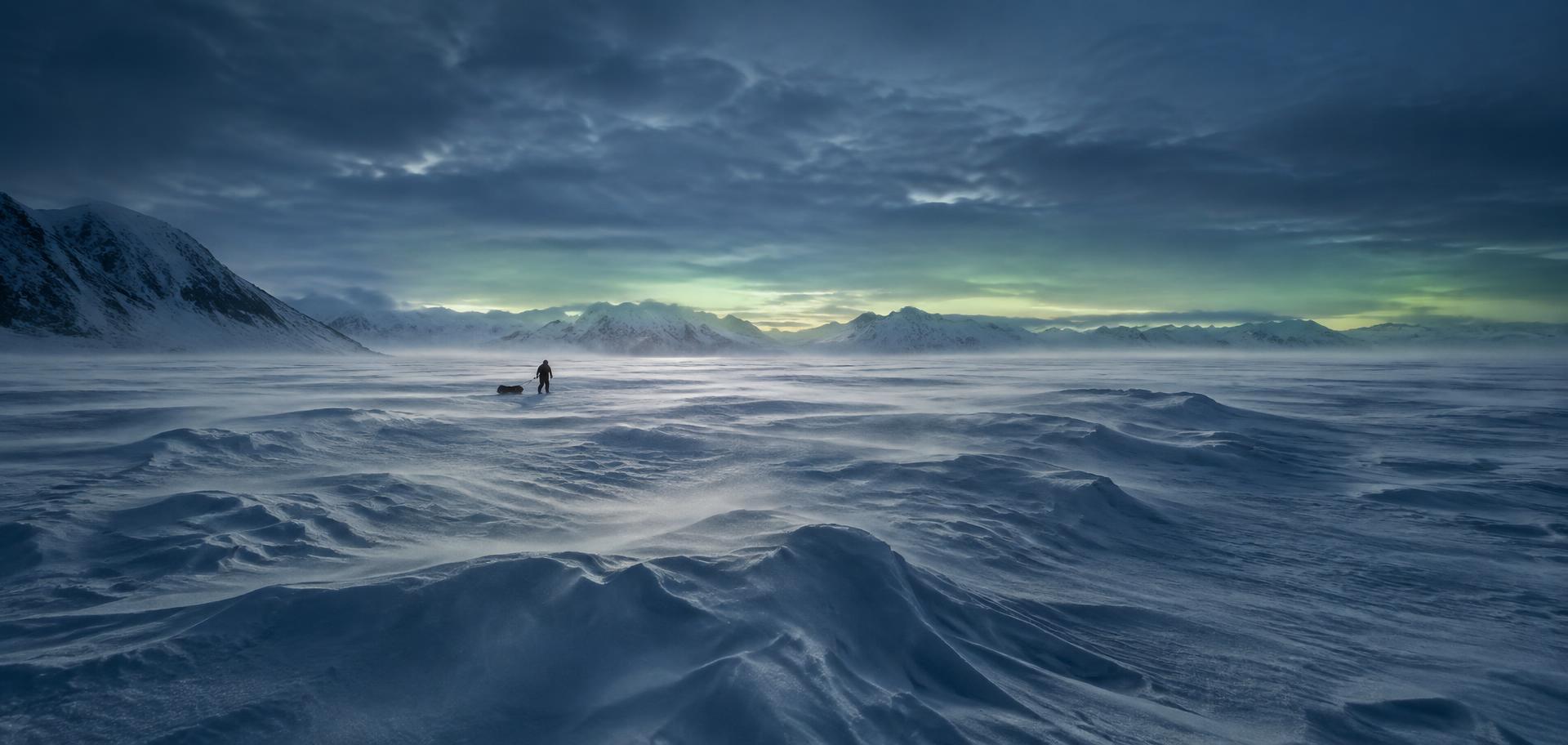 A snow-covered Arctic landscape under a wide grey sky